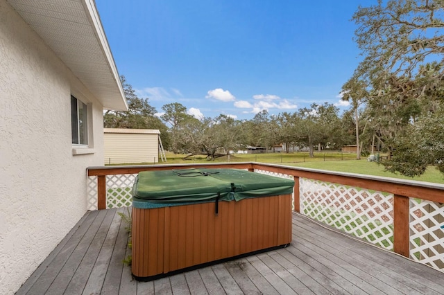 deck featuring a hot tub and a lawn