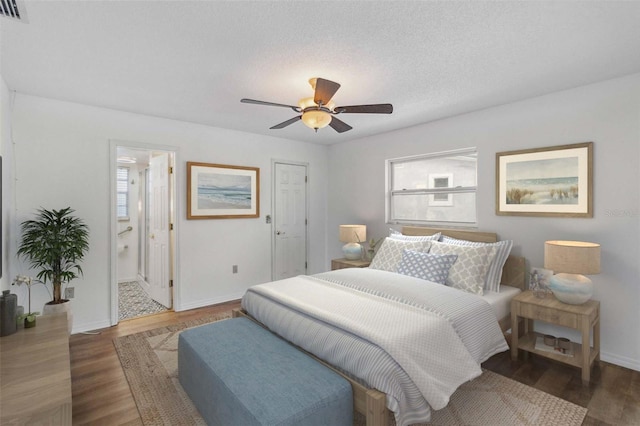 bedroom with hardwood / wood-style flooring, ceiling fan, connected bathroom, and a textured ceiling