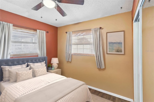 bedroom with ceiling fan, dark hardwood / wood-style floors, and a textured ceiling