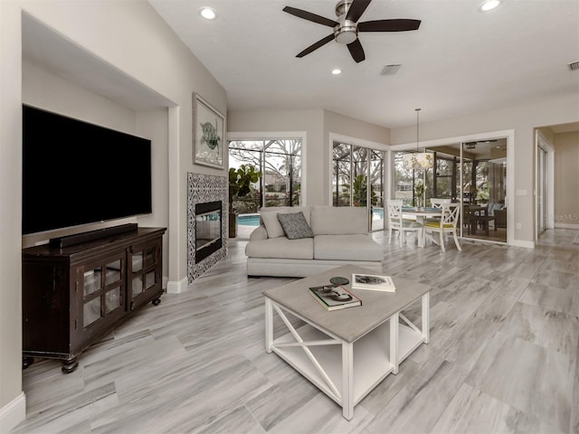 living room with a tile fireplace and ceiling fan