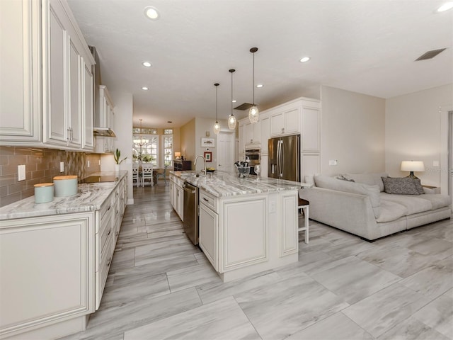 kitchen with hanging light fixtures, white cabinets, a large island, and stainless steel appliances