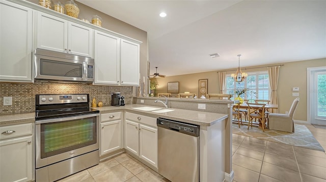 kitchen with light tile patterned floors, kitchen peninsula, appliances with stainless steel finishes, and white cabinetry