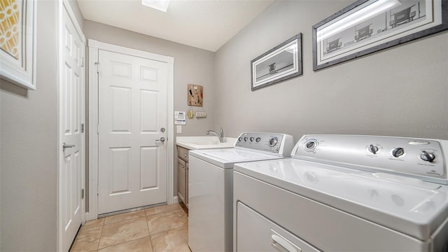 laundry area featuring cabinets, light tile patterned floors, washer and dryer, and sink