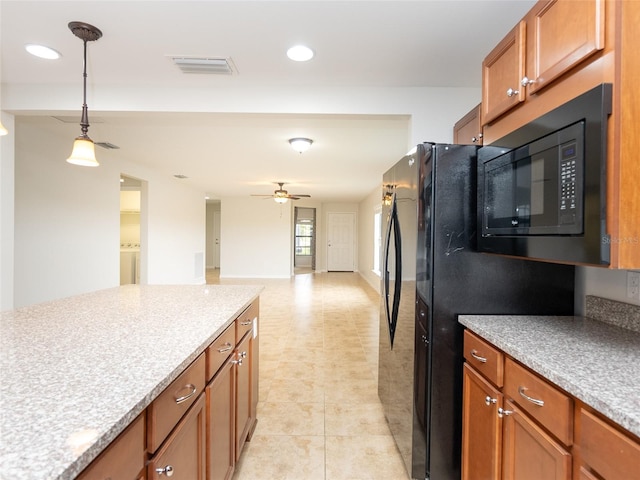 kitchen featuring hanging light fixtures, light tile patterned floors, ceiling fan, washer / clothes dryer, and black appliances