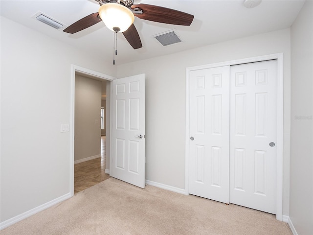 unfurnished bedroom with light colored carpet, a closet, and ceiling fan