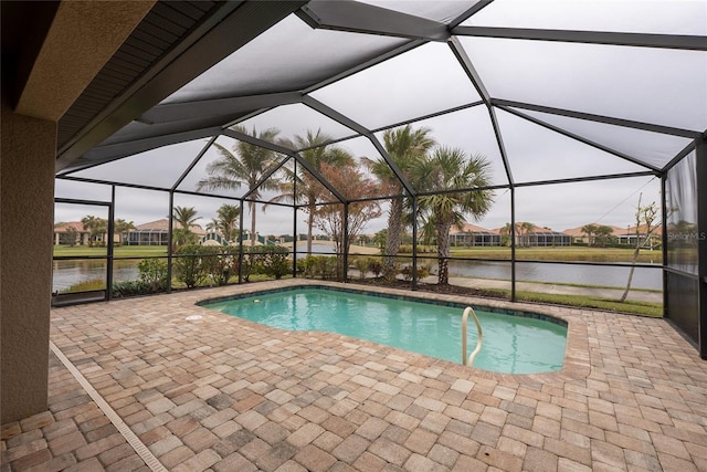 view of swimming pool featuring a patio, a water view, and glass enclosure