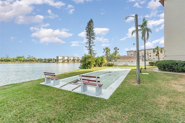 view of property's community with a water view and a lawn