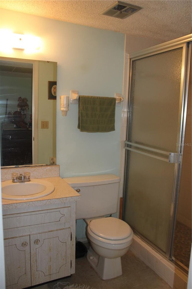 bathroom featuring vanity, a textured ceiling, tile patterned floors, toilet, and walk in shower