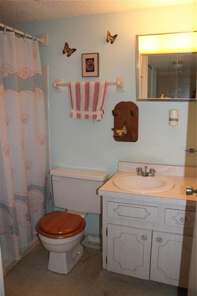 bathroom featuring vanity, toilet, tile patterned flooring, and a textured ceiling