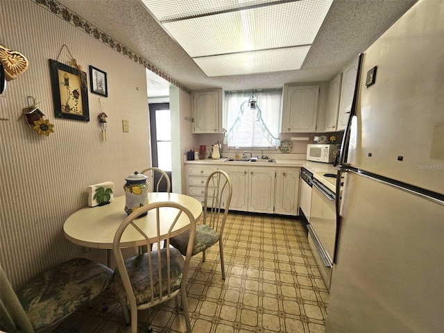 kitchen with refrigerator, sink, a textured ceiling, and electric range