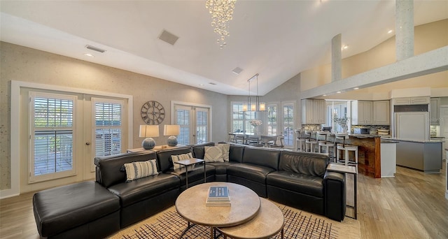 living room with lofted ceiling, light hardwood / wood-style floors, and french doors