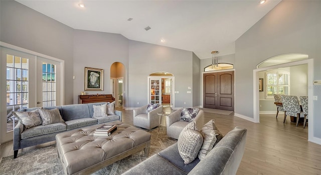 living room featuring high vaulted ceiling and light hardwood / wood-style floors