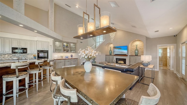 dining space featuring light wood-type flooring and high vaulted ceiling