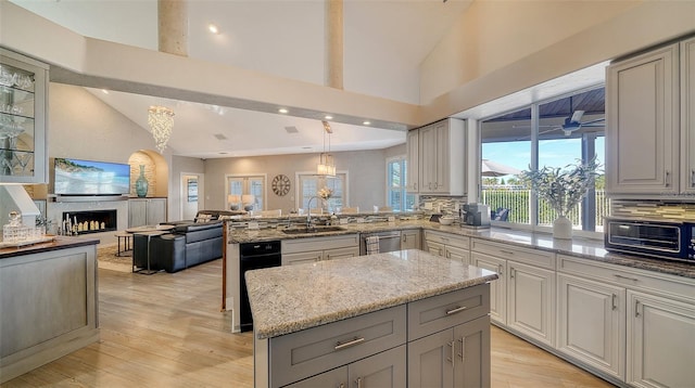 kitchen featuring sink, light stone counters, decorative light fixtures, a kitchen island, and decorative backsplash