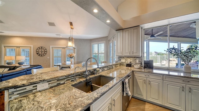 kitchen featuring pendant lighting, sink, lofted ceiling, light hardwood / wood-style flooring, and light stone counters