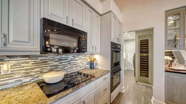 kitchen featuring white cabinets, light stone countertops, and black appliances