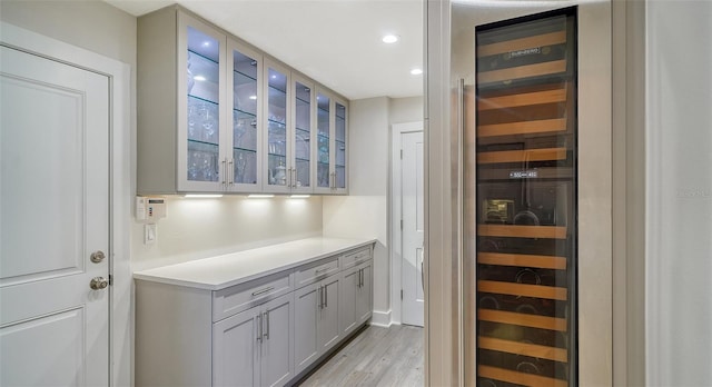 bar with beverage cooler and light wood-type flooring