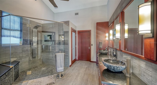 bathroom with ceiling fan, high vaulted ceiling, vanity, wood-type flooring, and walk in shower