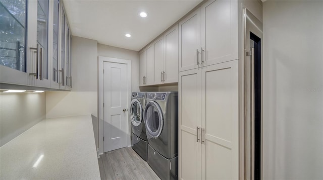 laundry area featuring cabinets, washing machine and dryer, and light wood-type flooring