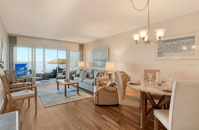 living room with hardwood / wood-style floors, a water view, and a chandelier