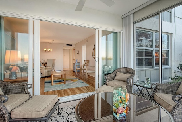 sunroom / solarium with ceiling fan with notable chandelier