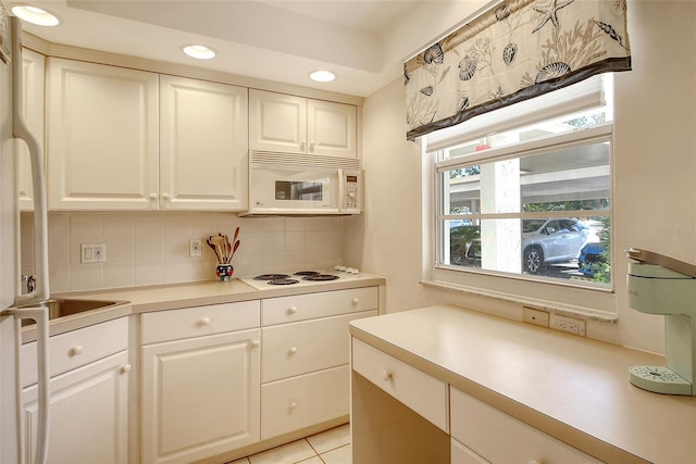 kitchen featuring white cabinets, light tile patterned floors, white appliances, and backsplash