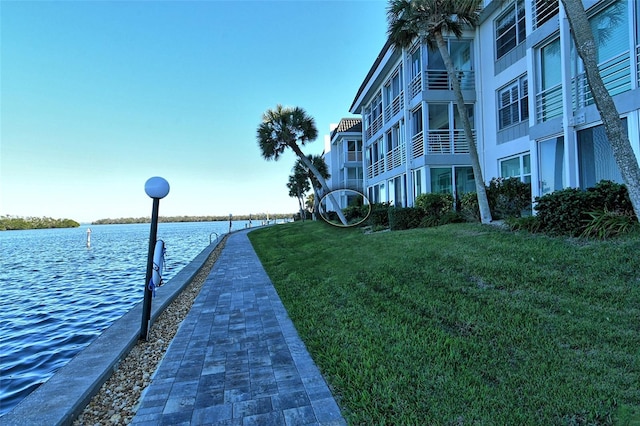 view of dock with a lawn and a water view