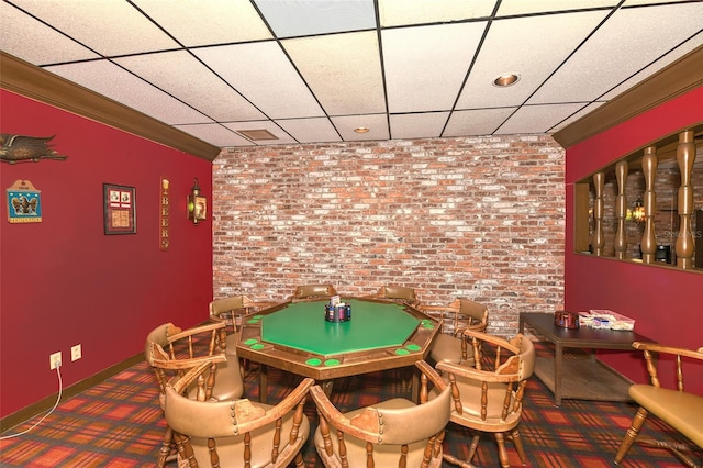 playroom featuring carpet flooring, a drop ceiling, ornamental molding, and brick wall