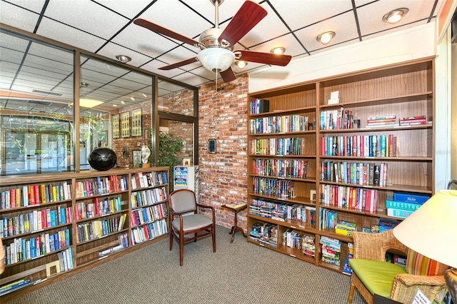 living area featuring carpet, a drop ceiling, and ceiling fan