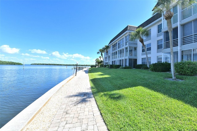 exterior space featuring a boat dock, a water view, and a yard