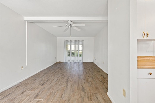 unfurnished living room featuring beamed ceiling, ceiling fan, and light wood-type flooring