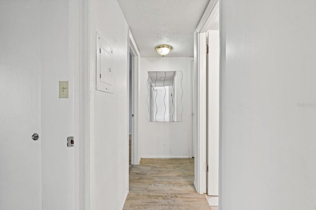 corridor with a textured ceiling and light hardwood / wood-style floors