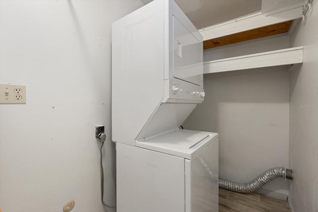 clothes washing area featuring hardwood / wood-style floors and stacked washer and clothes dryer