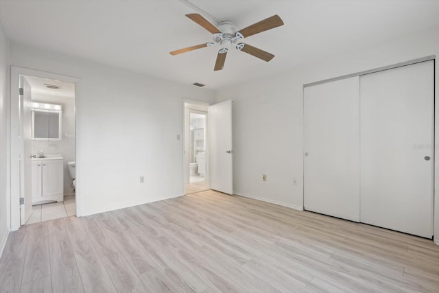 unfurnished bedroom featuring ceiling fan, connected bathroom, a closet, and light wood-type flooring