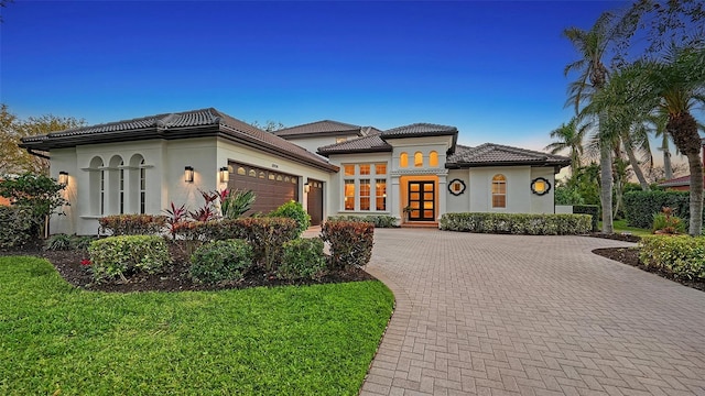 mediterranean / spanish home with french doors, a garage, and a front lawn