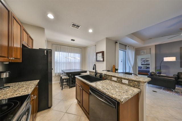 kitchen with decorative light fixtures, dishwasher, sink, an island with sink, and light stone counters