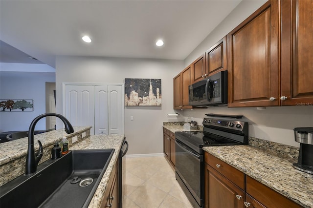 kitchen featuring light stone counters, sink, light tile patterned floors, and black appliances