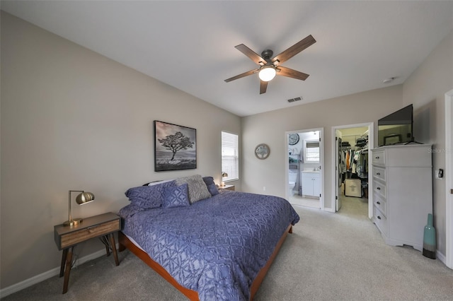 bedroom with ceiling fan, light colored carpet, a closet, and a walk in closet