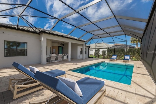 view of swimming pool featuring a patio, ceiling fan, and glass enclosure