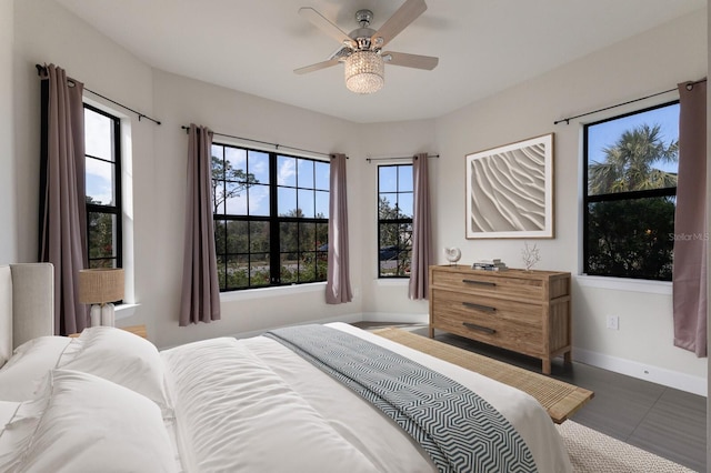 bedroom with ceiling fan, multiple windows, and dark tile patterned floors