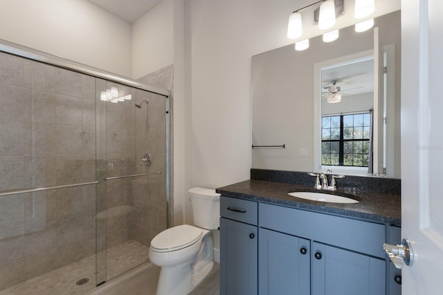 bathroom with vanity, ceiling fan, a shower with shower door, and toilet