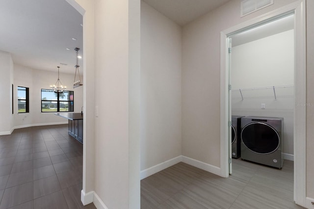 laundry area with an inviting chandelier and washing machine and clothes dryer