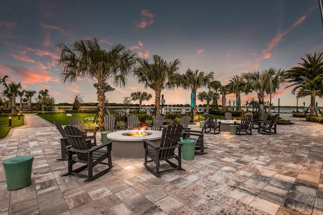 patio terrace at dusk featuring a water view and a fire pit