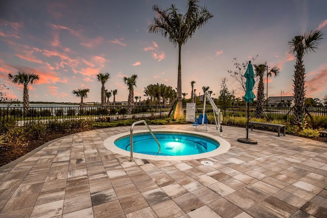 pool at dusk with a patio area and a community hot tub