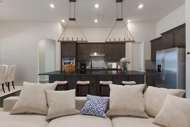 kitchen featuring stainless steel fridge with ice dispenser, hanging light fixtures, and a center island with sink