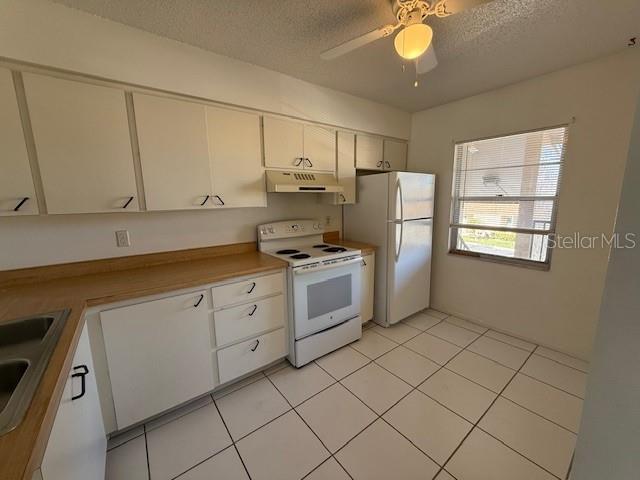 kitchen featuring white appliances, a textured ceiling, white cabinetry, ceiling fan, and sink