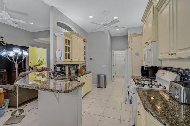 kitchen featuring ceiling fan, white appliances, a kitchen breakfast bar, and cream cabinetry