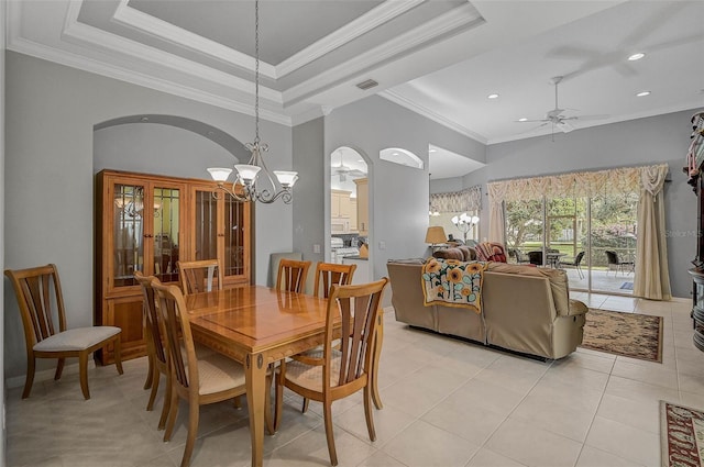 dining space with a raised ceiling, ornamental molding, ceiling fan with notable chandelier, and light tile patterned flooring