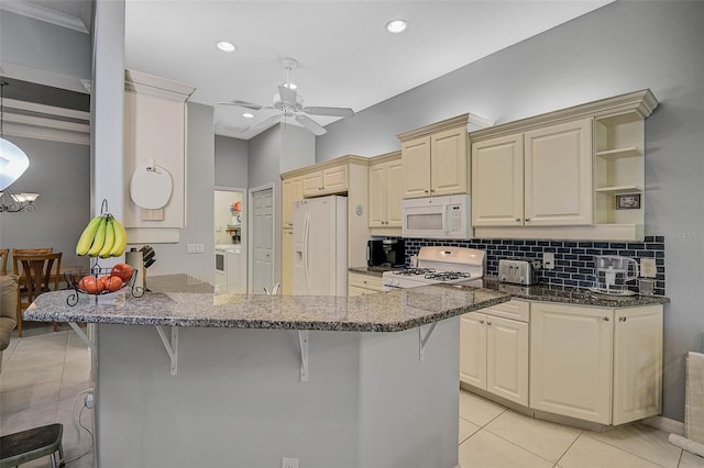 kitchen with a breakfast bar area, white appliances, light tile patterned floors, kitchen peninsula, and ceiling fan