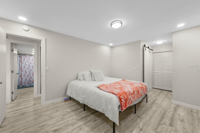 bedroom featuring a closet, a barn door, and light wood-type flooring